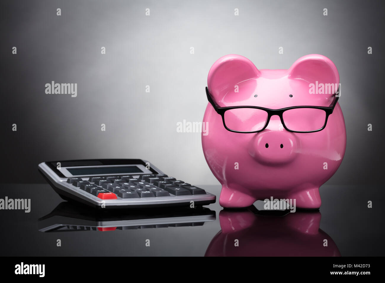 Close-up of Pink Piggy Bank et Calculatrice sur fond gris Banque D'Images
