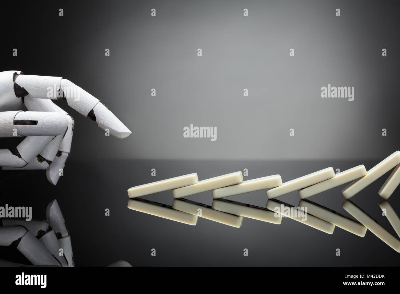 Main robotique poussant dominos sur fond gris Banque D'Images