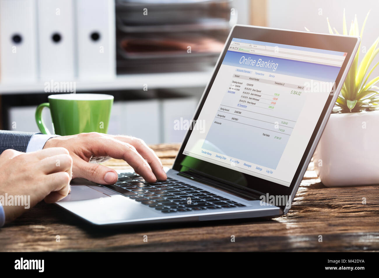 Close-up de la main de l'homme d'affaires Effectuez des opérations bancaires en ligne sur ordinateur portable sur un bureau en bois Banque D'Images