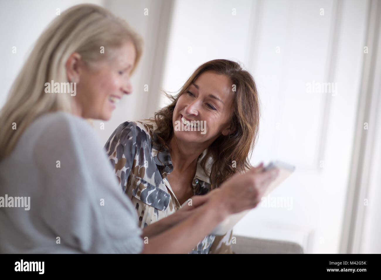 Femme mature à la recherche d'amis à une tablette numérique Banque D'Images