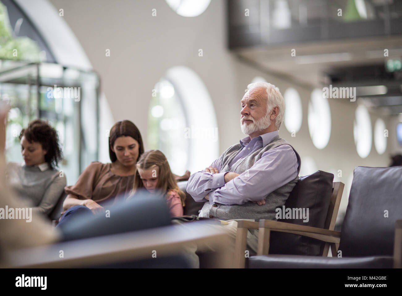 Senior Male en attente dans une salle d'attente hôpital bondé Banque D'Images