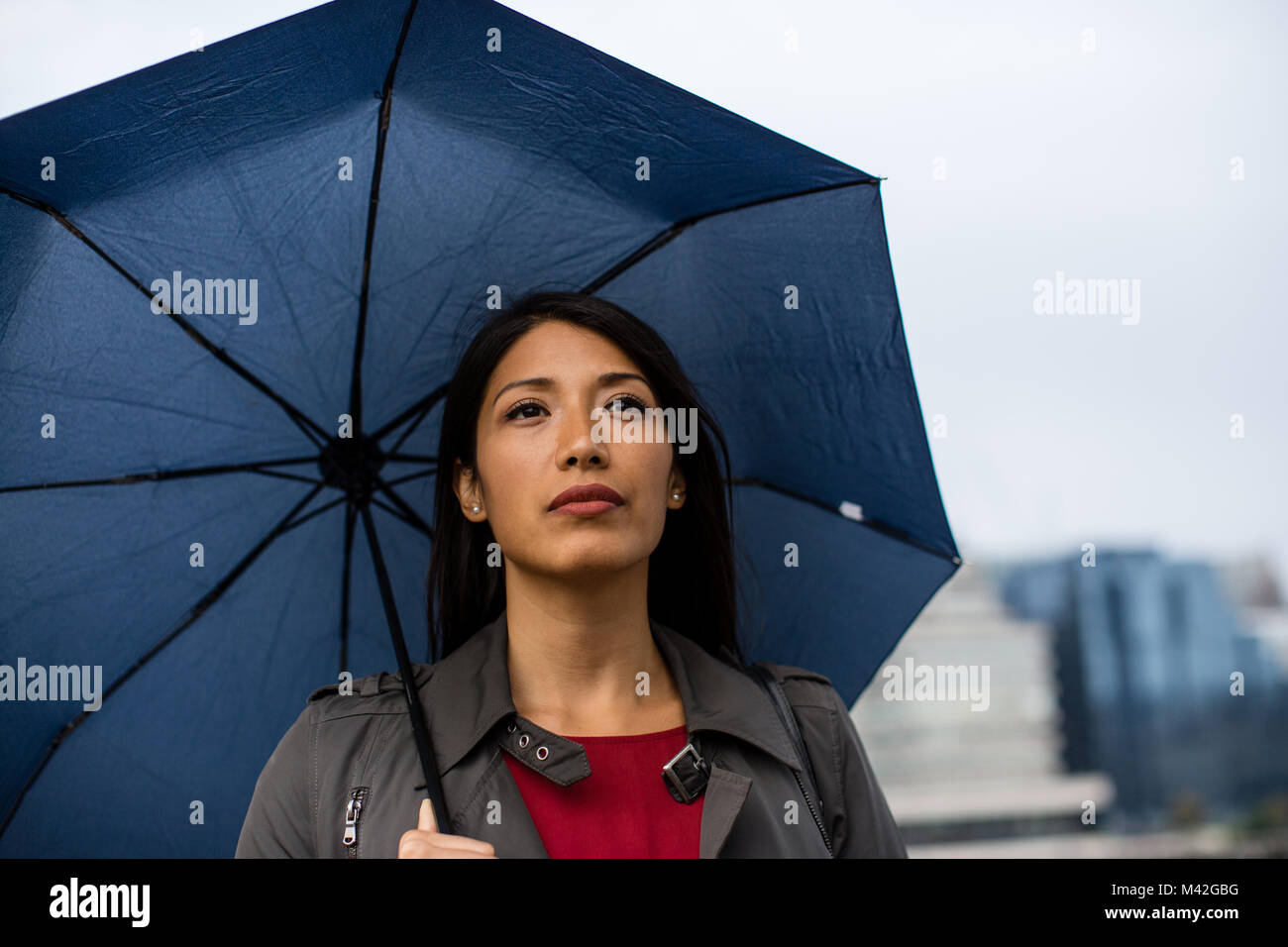 Businesswoman in city holding umbrella par mauvais temps Banque D'Images
