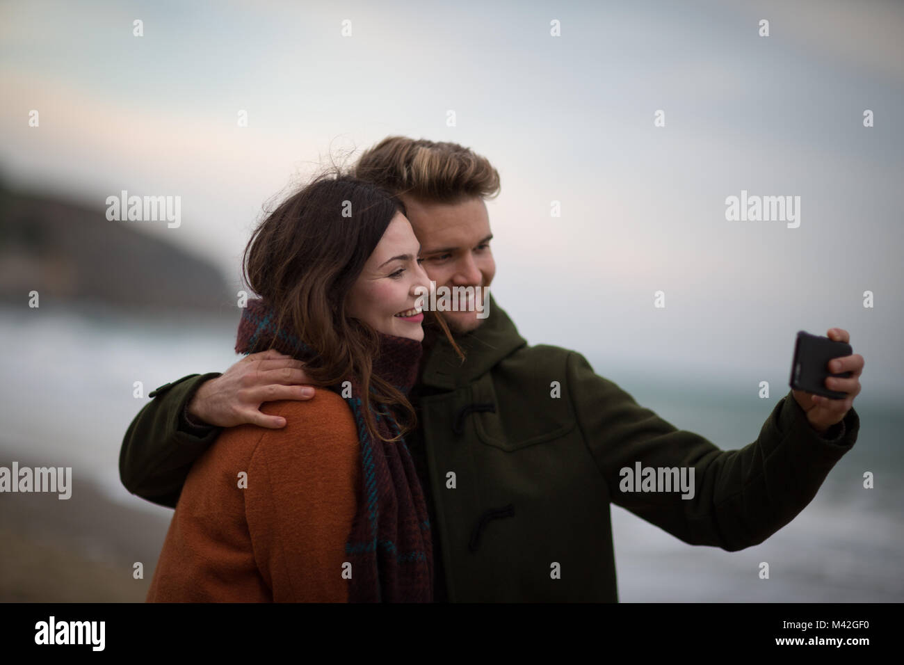 Young adult couple prenant une plage de selfies Banque D'Images