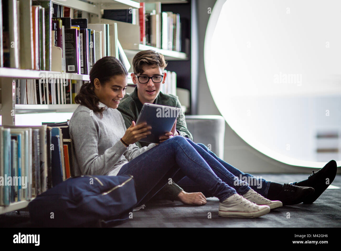 La lecture les élèves digital tablet in library Banque D'Images