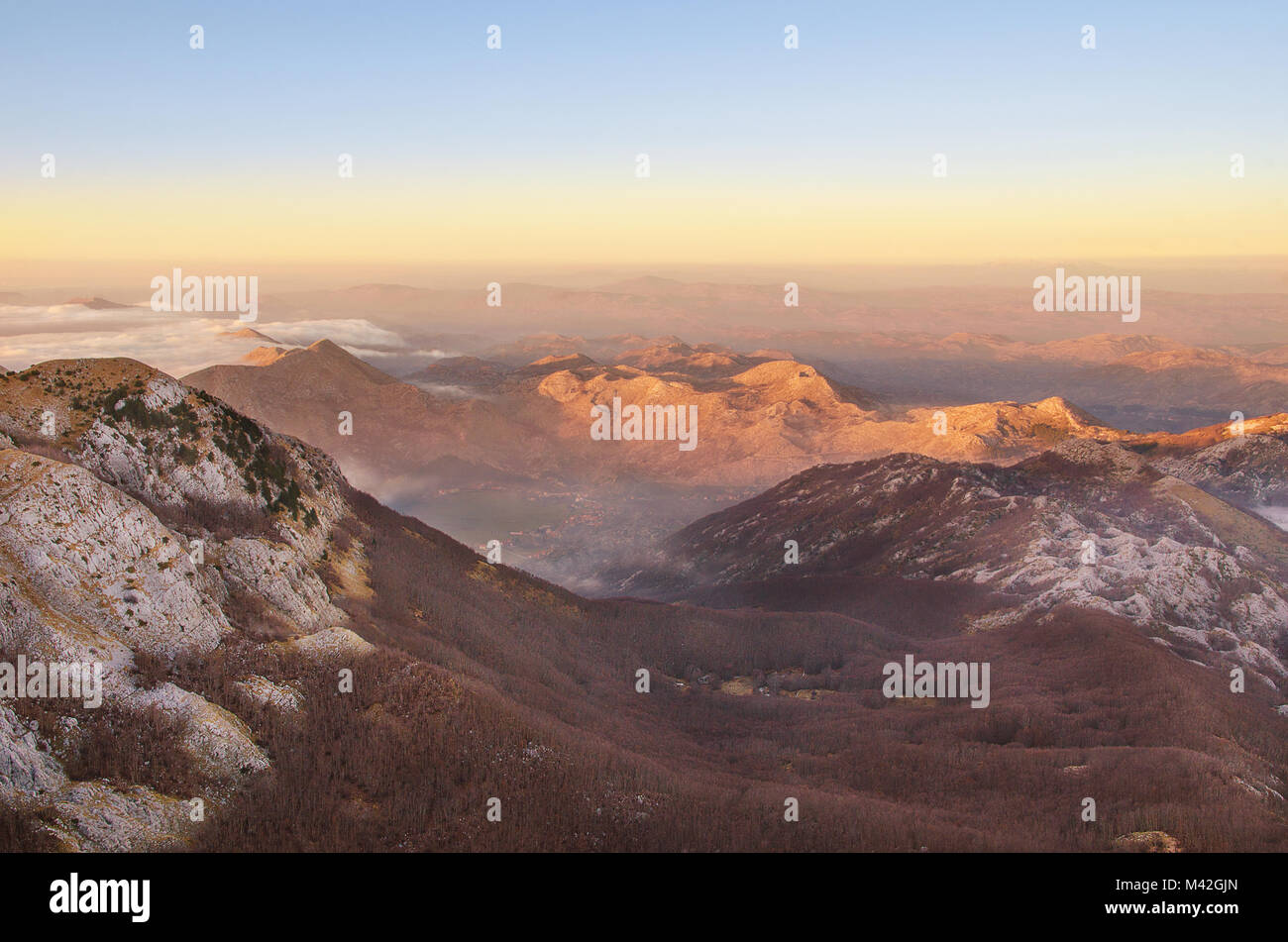 Vue au-dessus des nuages de la montagne de la vallée de l'échelle de Lovcen et des pics de montagne au coucher du soleil. Banque D'Images