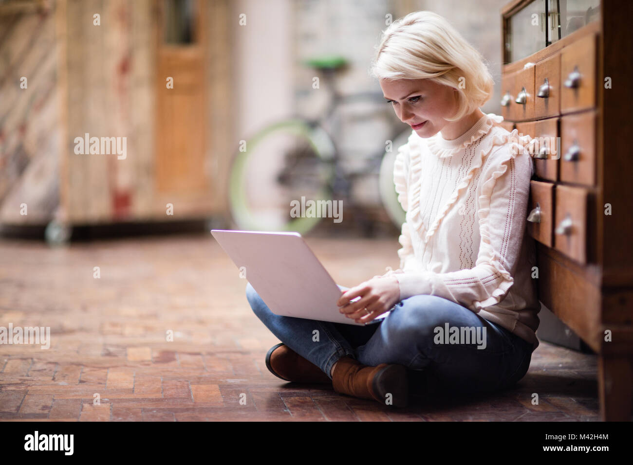 Les jeunes femelles adultes sitting on floor working on laptop Banque D'Images