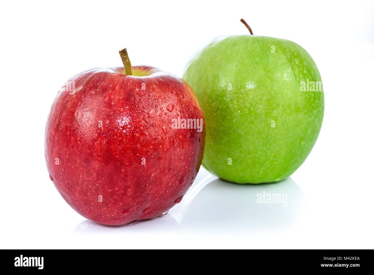 Deux pommes fraîches en rouge et de couleur verte avec des gouttes d'eau et isolé sur un fond blanc. Banque D'Images