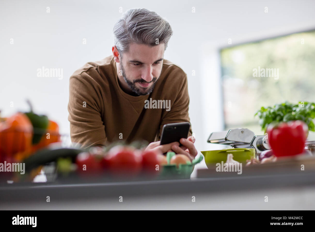 La recherche de mâles adultes fiche sur smartphone dans la cuisine Banque D'Images