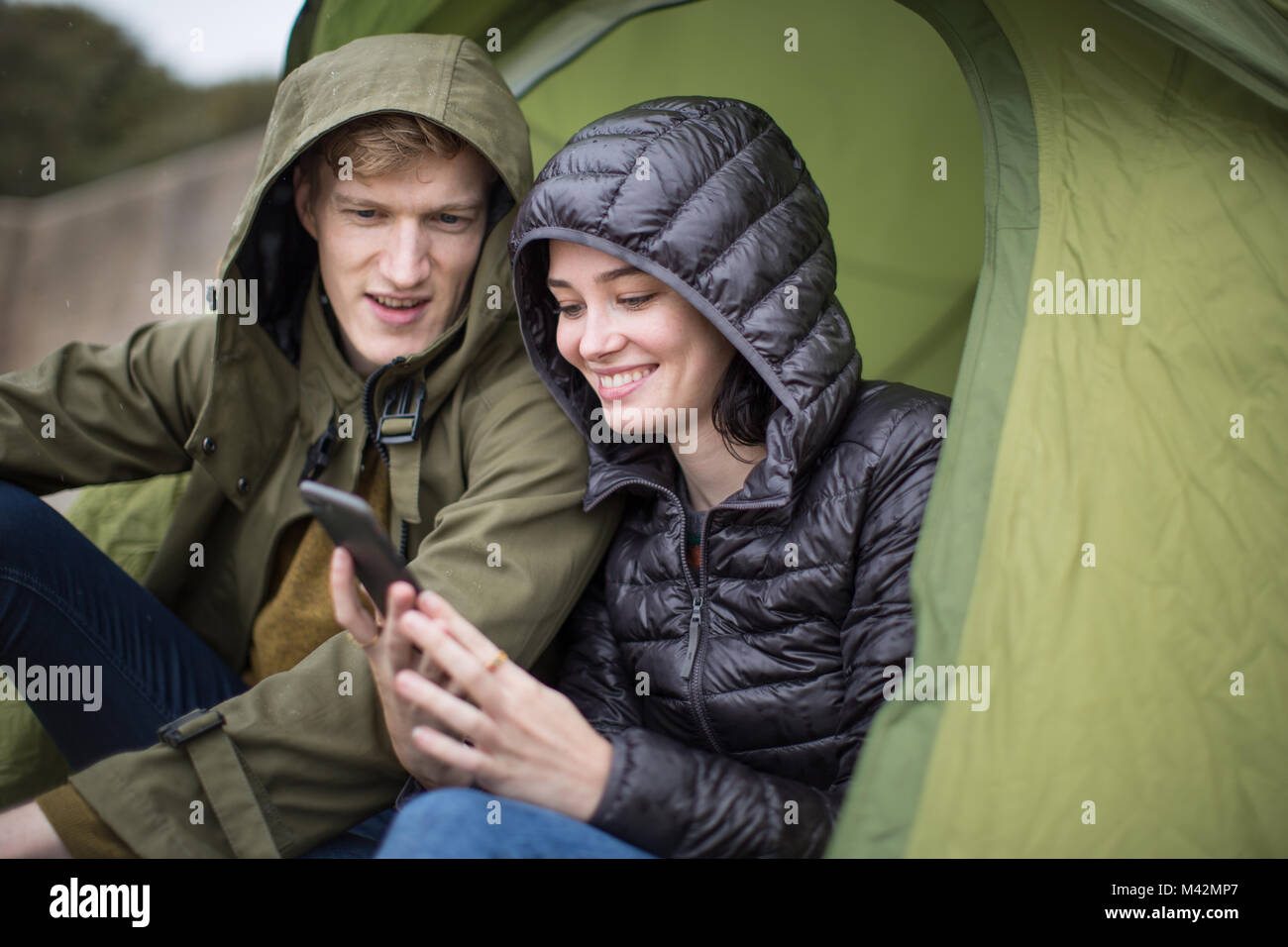 Jeune couple à l'aide d'un smartphone sur un voyage de camping Banque D'Images