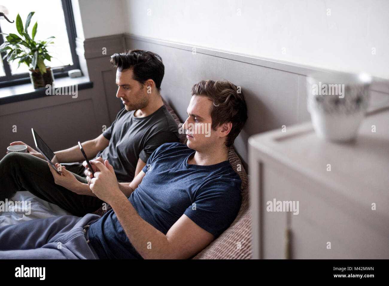Jeune homme couple using smartphone et tablette numérique Banque D'Images