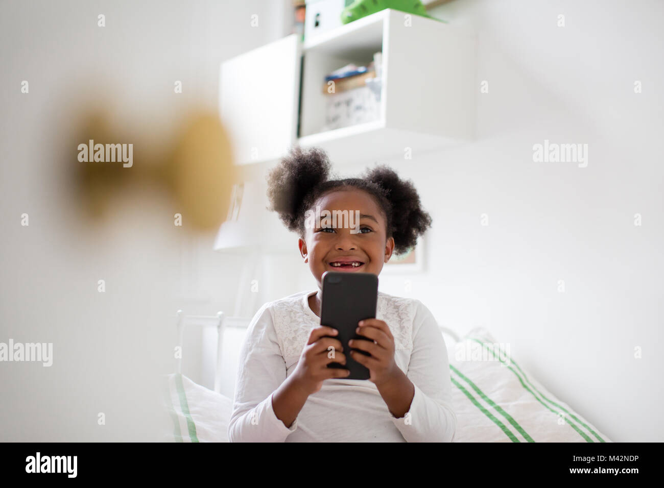Girl Playing with smartphone dans sa chambre à coucher Banque D'Images