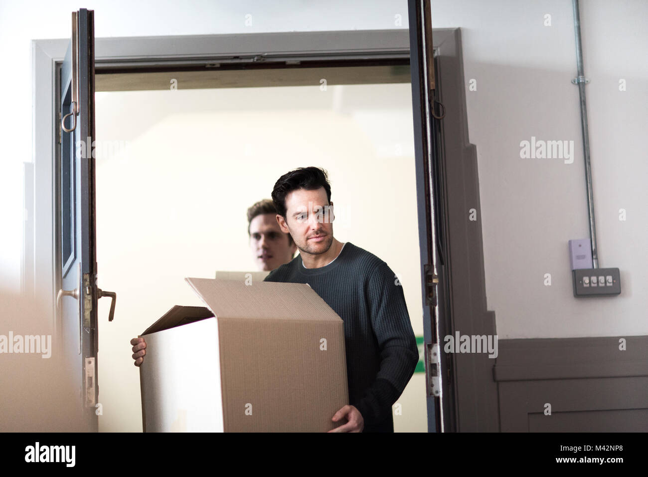 Jeune homme couple déménagement accueil Banque D'Images