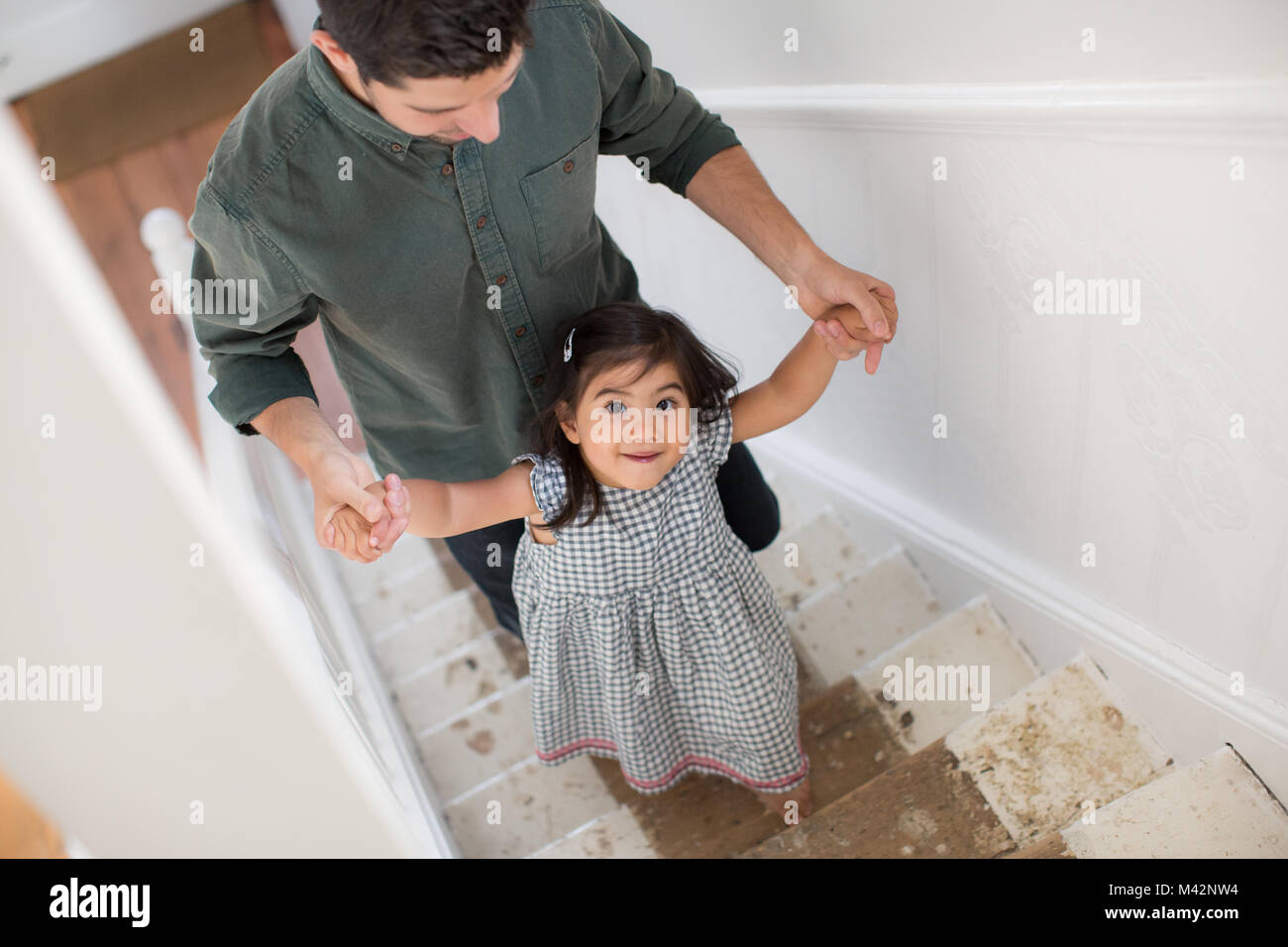 Père fille aidant à pied vers le haut des escaliers Banque D'Images