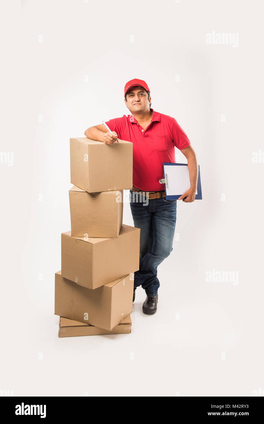 Concept de livraison - Portrait of Happy Indian ou delivery Man en rouge ou  vert marche uniforme ou de sauter ou de contrôle ou la présentation de  boîte en carton avec co