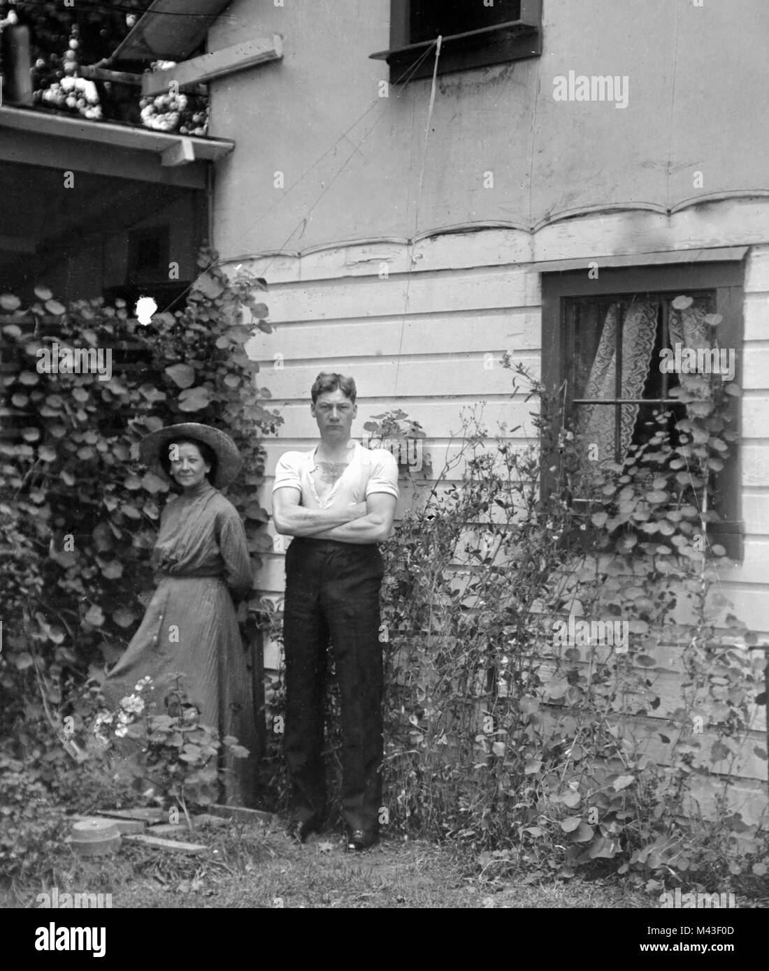 Un couple marié se tenir dans leur jardin à côté de la maison familiale, ca. 1910. Banque D'Images