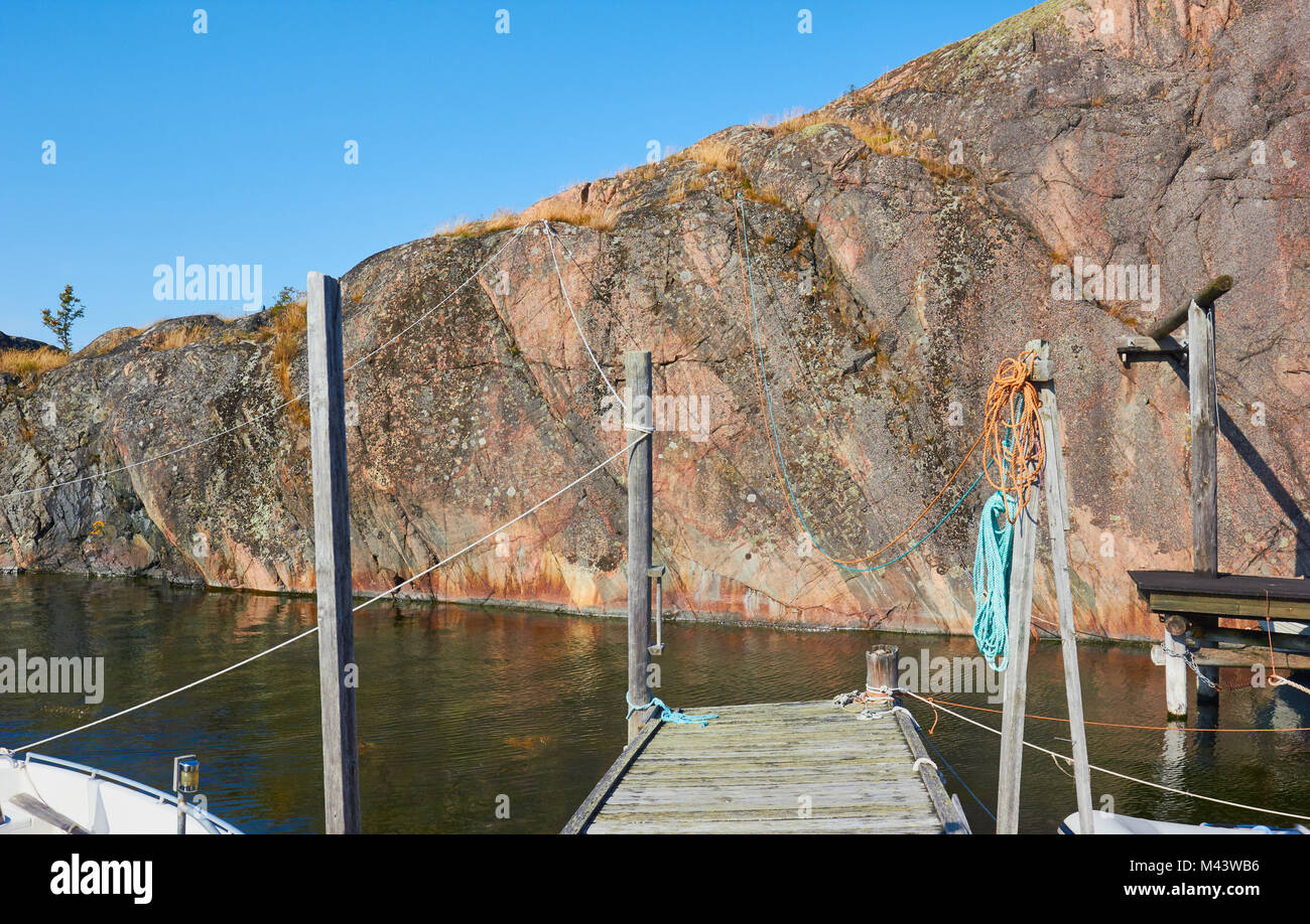 Mur de roche et jetée en bois rustique dans petit port sur la côte de la mer Baltique, la Suède, Scandinavie Banque D'Images