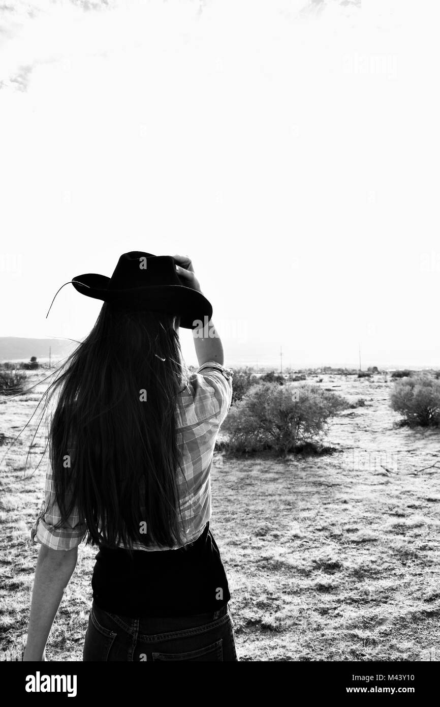 Country Girl In Desert Holding Hat noir et blanc Banque D'Images