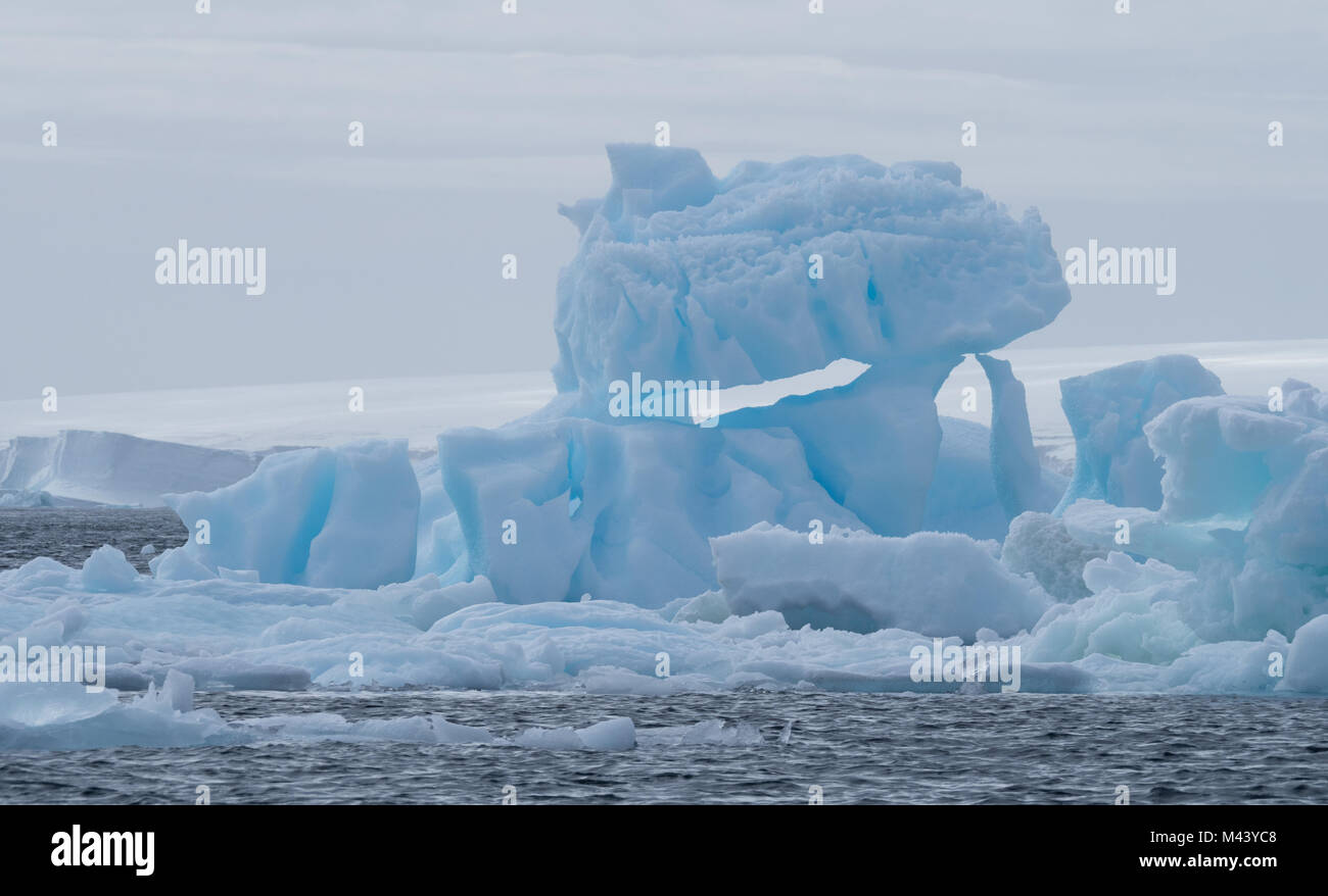 Un iceberg bleu flottant dans l'eau gris foncé de l'océan Austral au son de l'Antarctique. Ciel couvert est ci-dessus. Banque D'Images