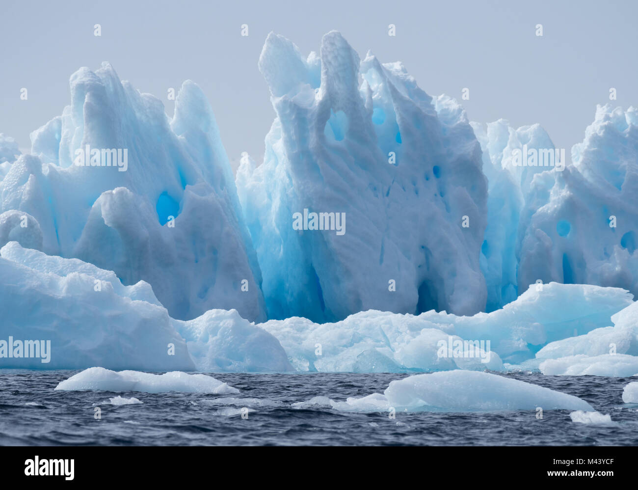 Un léger, moyen et bleu foncé iceberg flottant dans l'eau gris foncé de l'océan Austral au son de l'Antarctique. Ciel couvert est ci-dessus. Banque D'Images