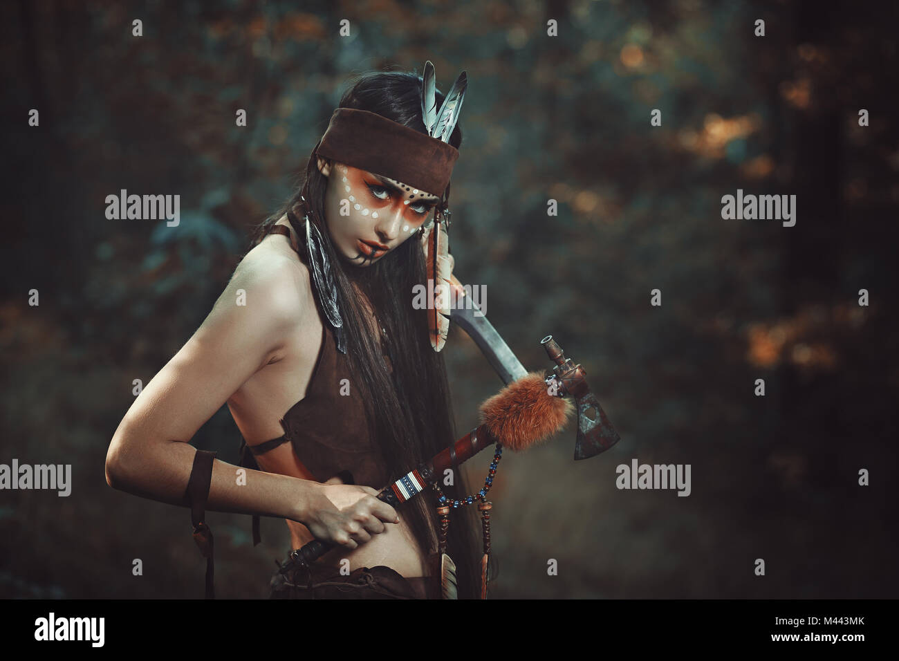 American Indian Warrior avec tomahawk. Arrière-plan de la forêt Banque D'Images
