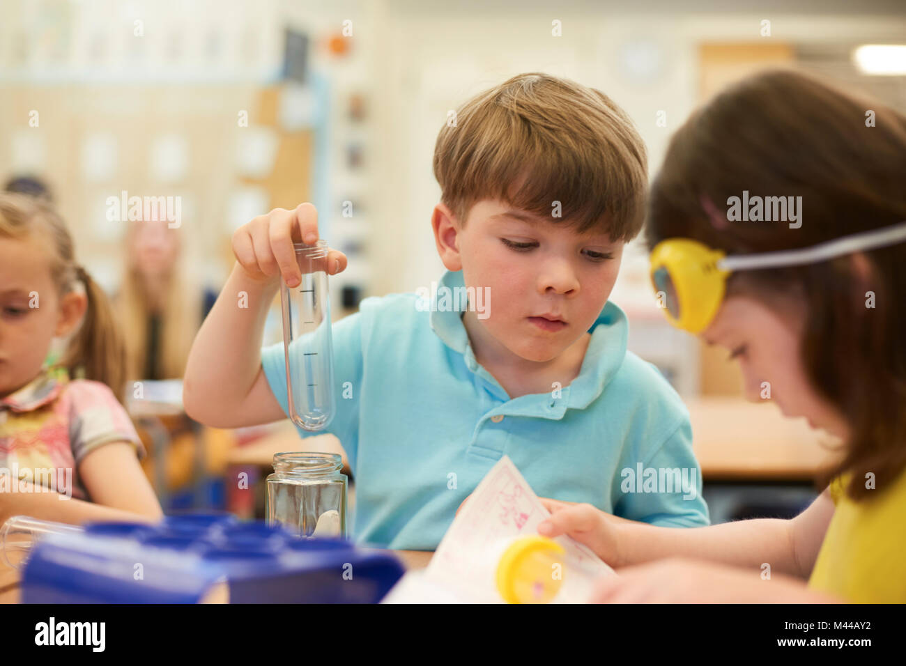 Primary schoolboy et filles faisant test tube experiment in classroom Banque D'Images