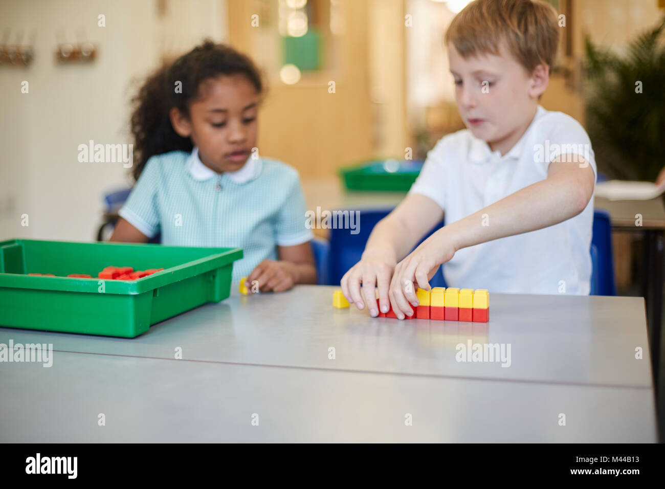 Fille et écolier la construction de blocs de jouets dans la salle de classe à l'école primaire Banque D'Images