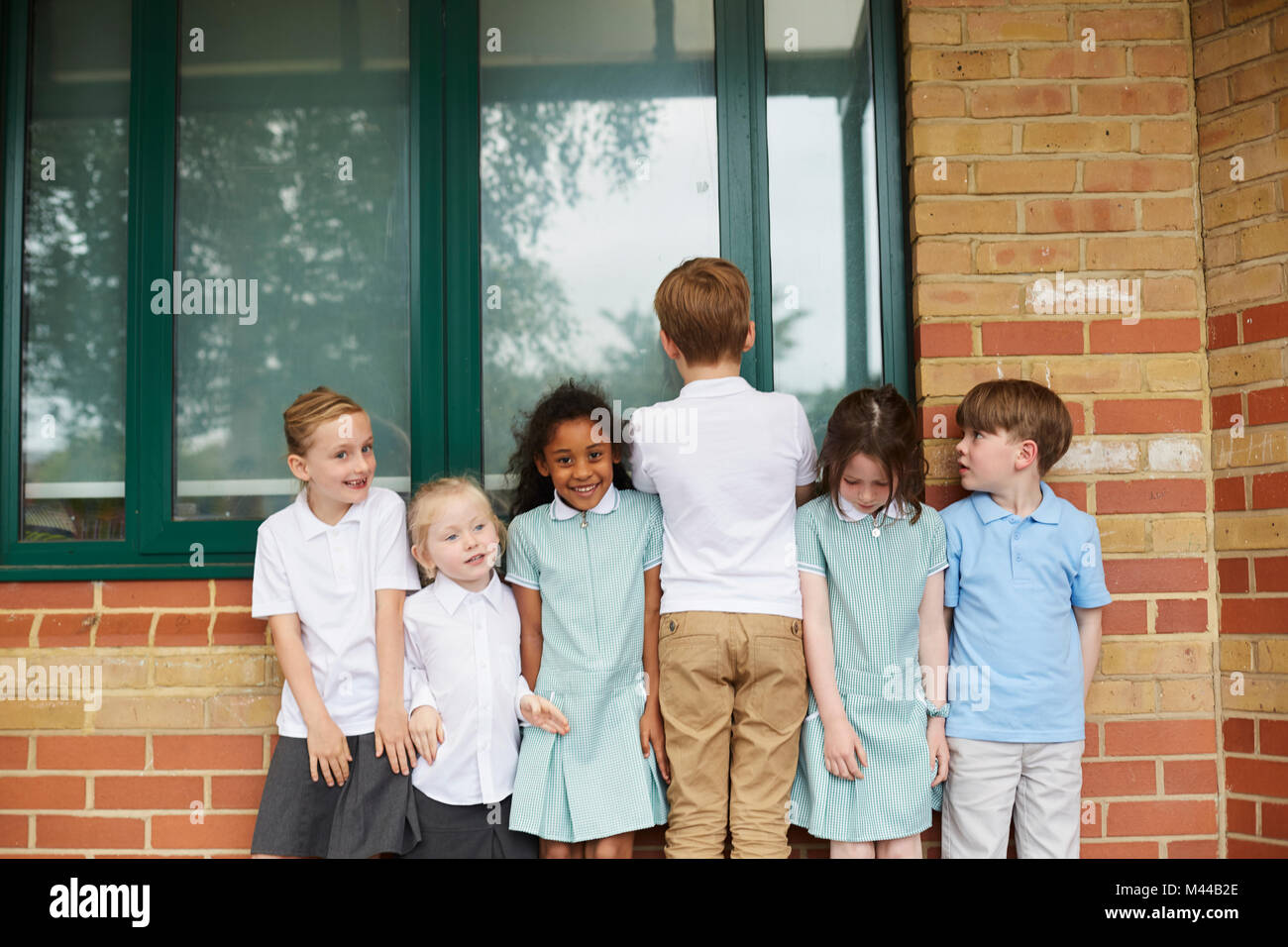 Les écolières et les garçons debout dans une rangée à l'extérieur du bâtiment de l'école primaire, portrait Banque D'Images