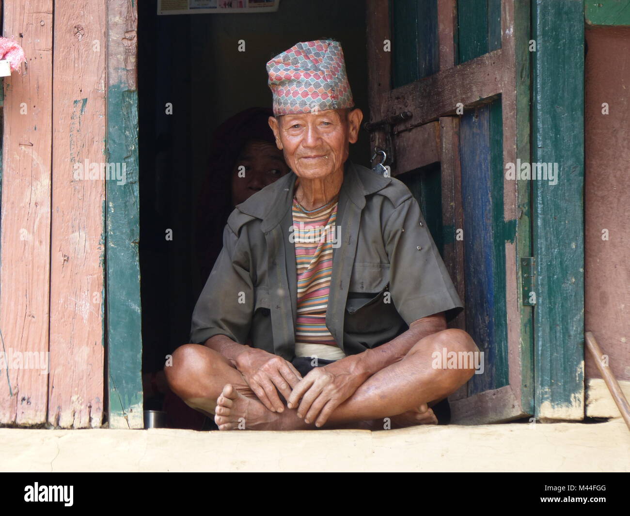 Tallo Chipla, Népal, le 7 septembre 2015 : Vieil homme assis à doorsill - rencontre la population locale lors du circuit de l'Annapurna trek au Népal Banque D'Images