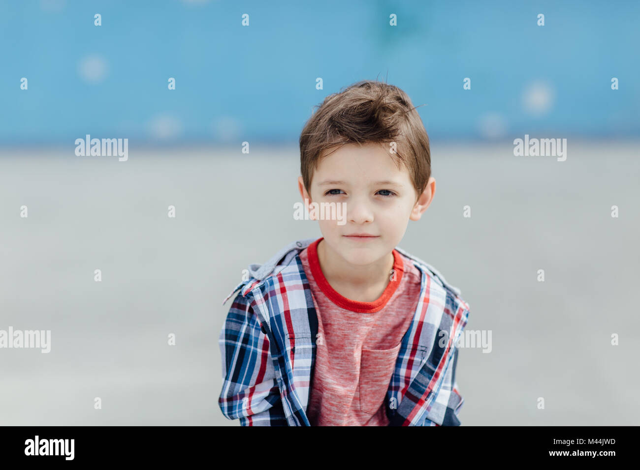 Vue de face d'un garçon de 6 ans qui pose à l'extérieur et faire une pause Banque D'Images