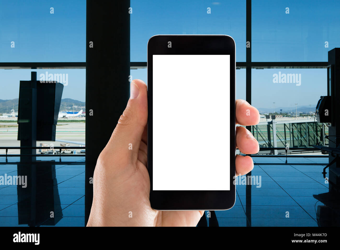 Gros plan du hand holding mobile phone avec écran blanc in airport Banque D'Images