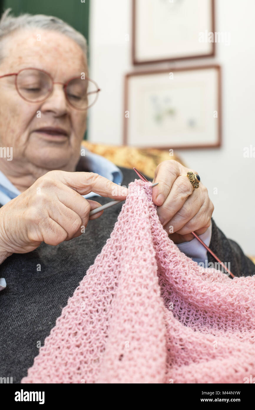 Femme âgée détendu au point sélective sur les mains accueil tricot laine rose gros plan Banque D'Images