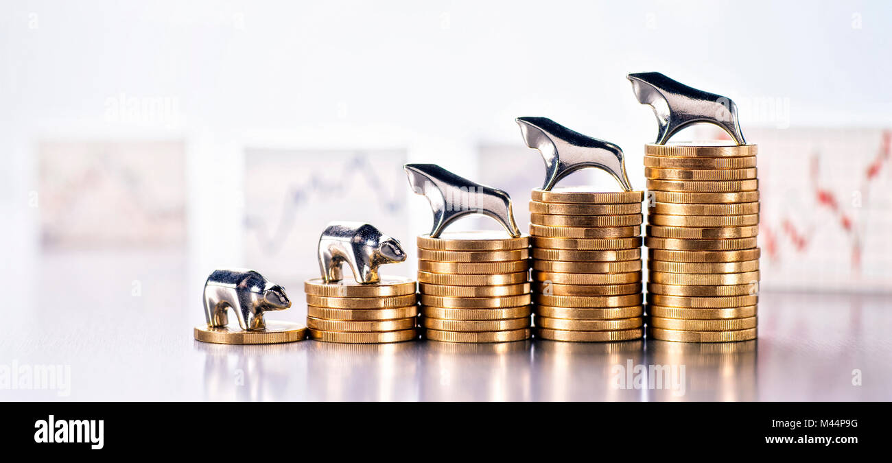 Pile de pièces avec Bull et Bear et les graphiques avec les prix du marché dans l'arrière-plan Banque D'Images