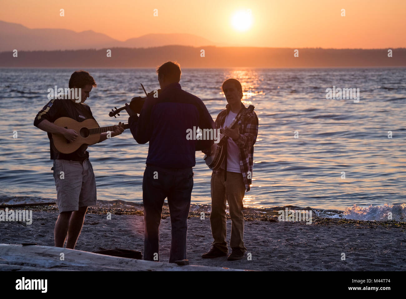 États-unis, Washington, Seattle, Parc Carkeek, Musians jouant au coucher du soleil le Puget Sound et les montagnes olympiques en arrière-plan Banque D'Images