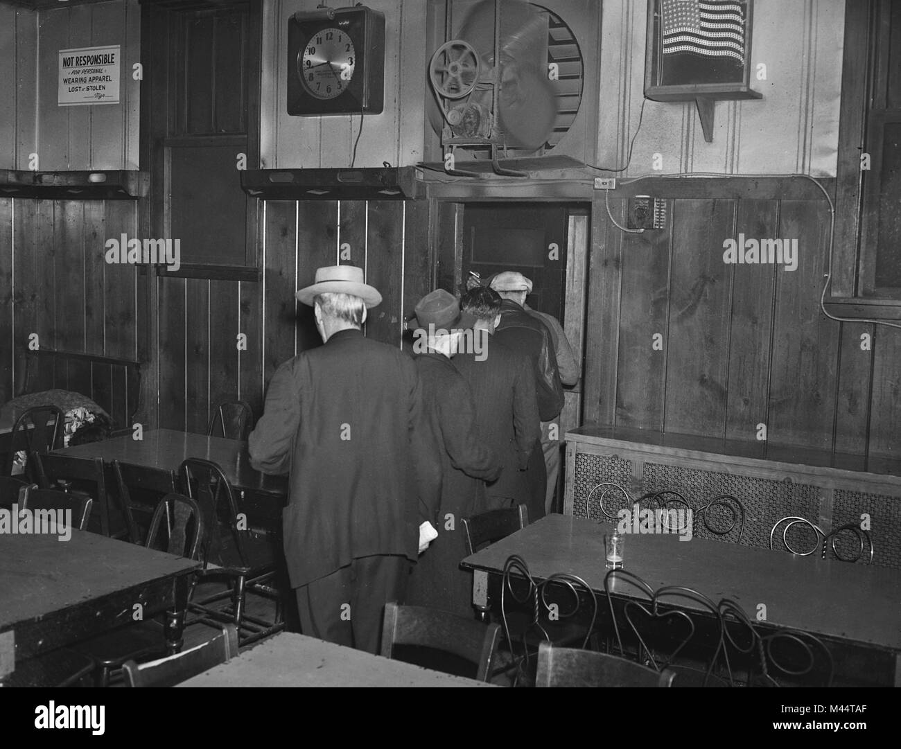 Les hommes anonymes slink hors d'un bar de Chicago lors d'un raid de jeu, ca. 1955. Banque D'Images