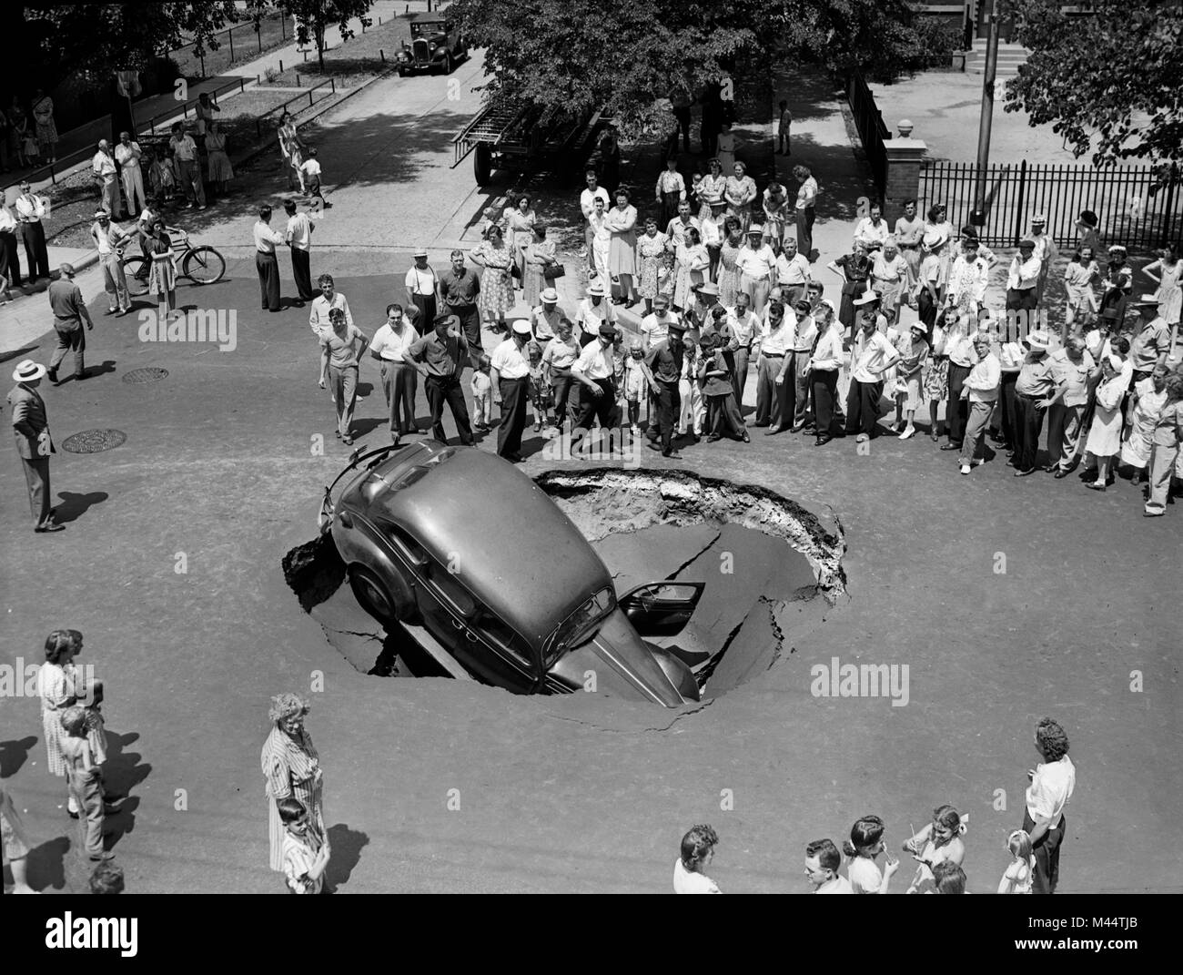 Une foule se rassemble autour d'un gouffre qui avale une voiture à Chicago, ca. 1947. Nom de fichier : Banque D'Images