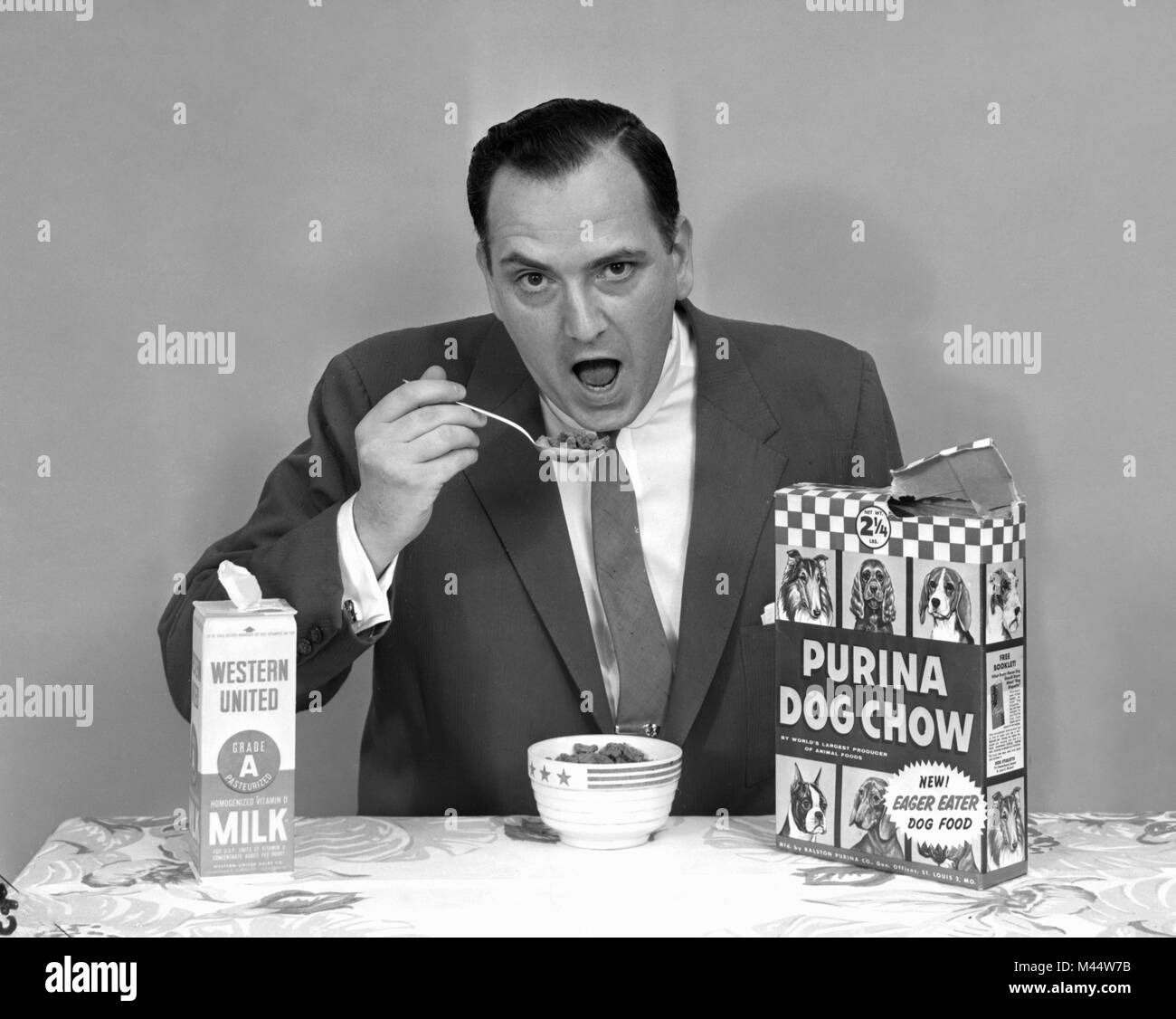 Un homme fait semblant de manger de la nourriture pour chiens, ca. 1962. Banque D'Images