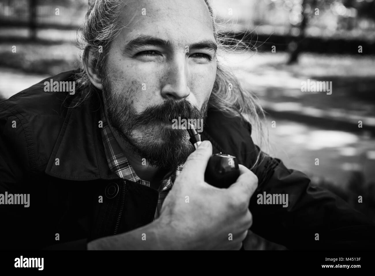 Homme asiatique barbu fume une pipe, noir et blanc portrait visage avec selective focus Banque D'Images