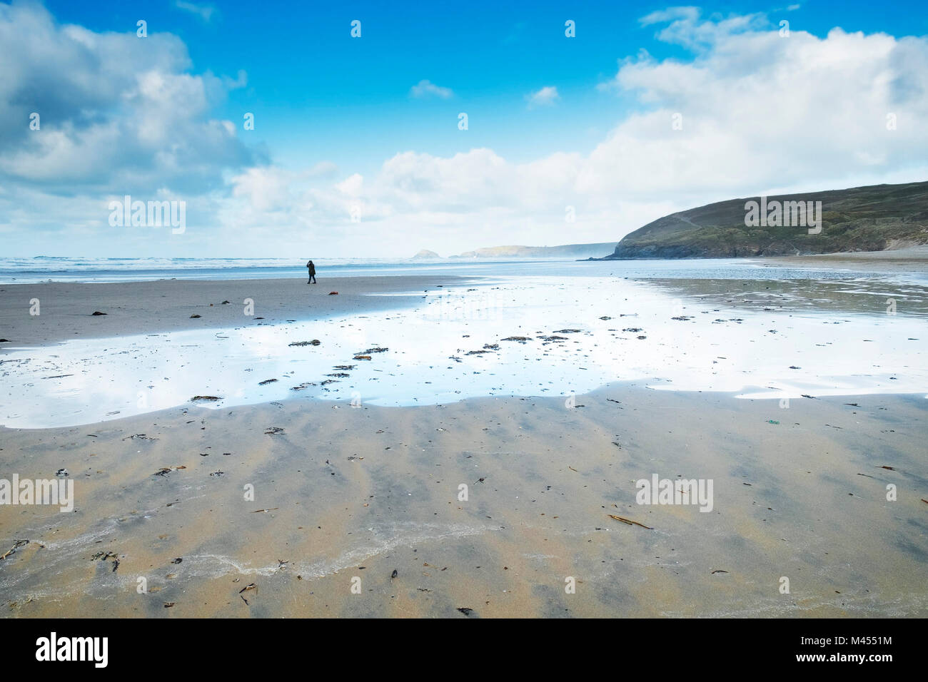 Une figure de marcher sur une plage déserte Rolvenden Cornwall UK. Banque D'Images