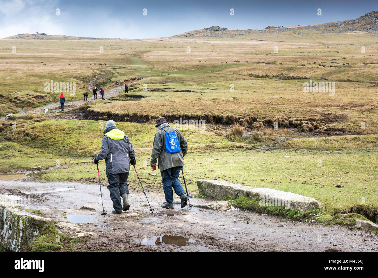 Les marcheurs à l'aide de bâtons de randonnée sur une piste boueuse à Rough Tor sur Bodmin Moor en Cornouailles. Banque D'Images
