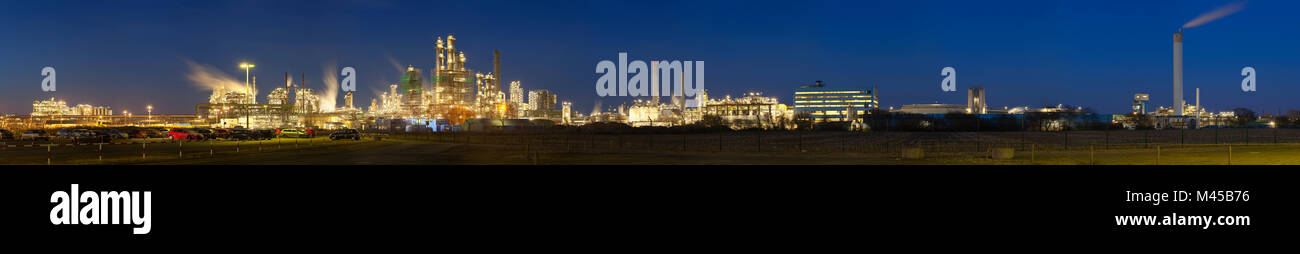 Panorama d'une raffinerie de pétrole avec le bleu ciel de nuit, un parking à l'avant-plan. Banque D'Images