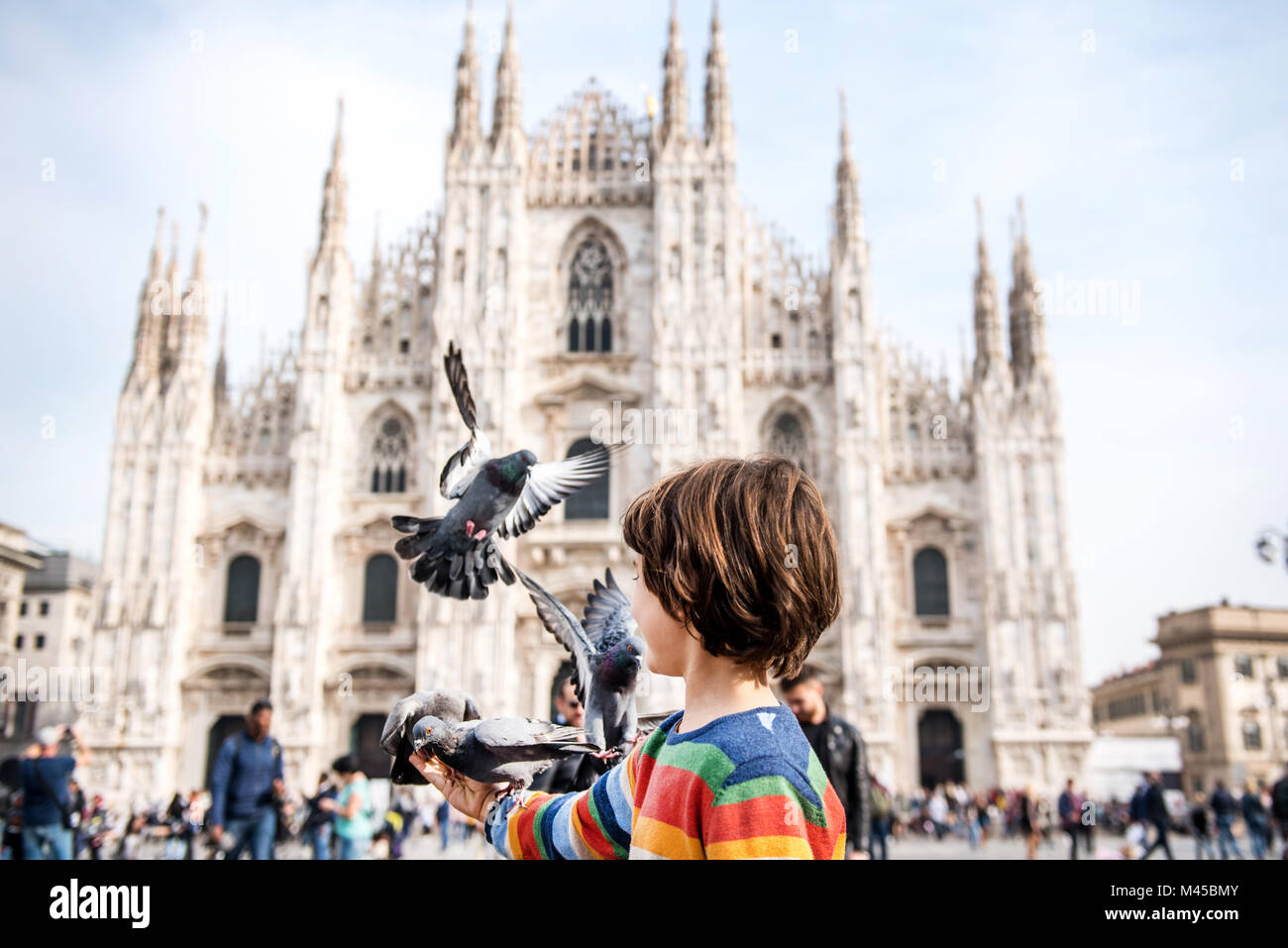 Boy feeding pigeons dans la place de la cathédrale de Milan, Milan, Lombardie, Italie Banque D'Images