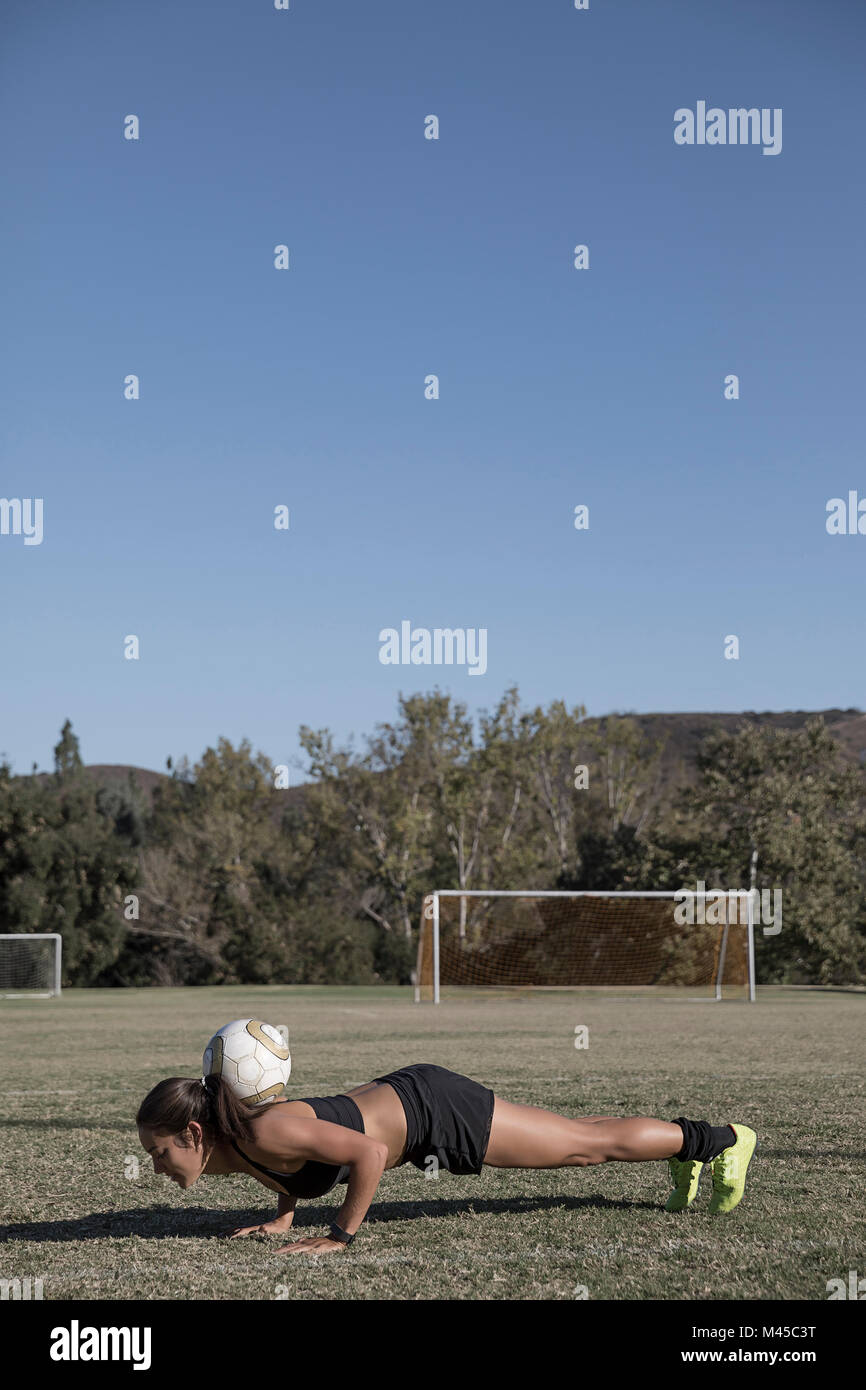 Femme sur un terrain de football faire appuyez sur haut avec football Banque D'Images