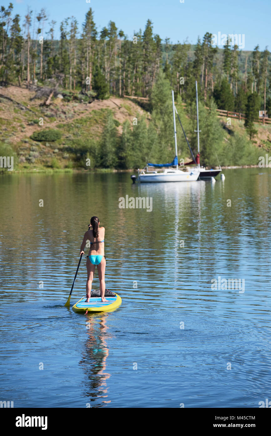Vue arrière du jeune femme stand up paddleboarding sur le lac, Frisco, Colorado, USA Banque D'Images