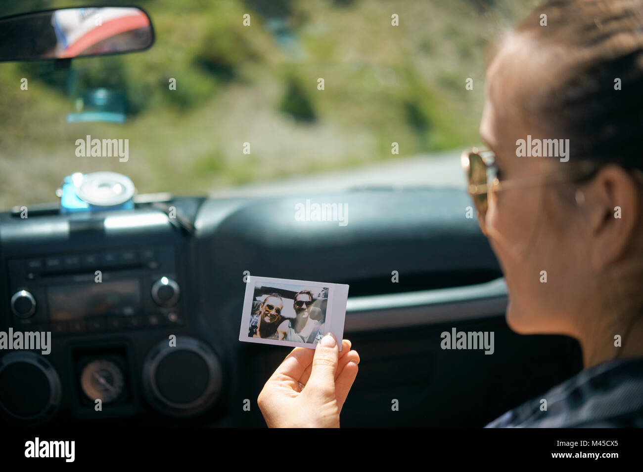 Plus d'épaule de jeune femme on road trip holding instant photographie avec copain, Breckenridge, Colorado, USA Banque D'Images