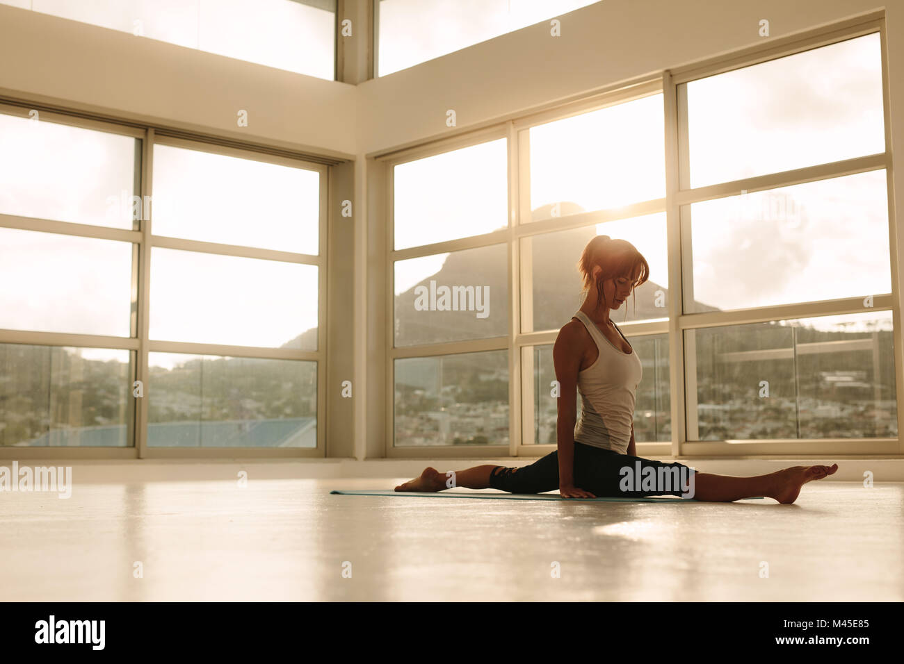 Fit woman practicing yoga jambe split posent au studio de remise en forme. Les femmes faisant du yoga dans une salle de sport. Banque D'Images