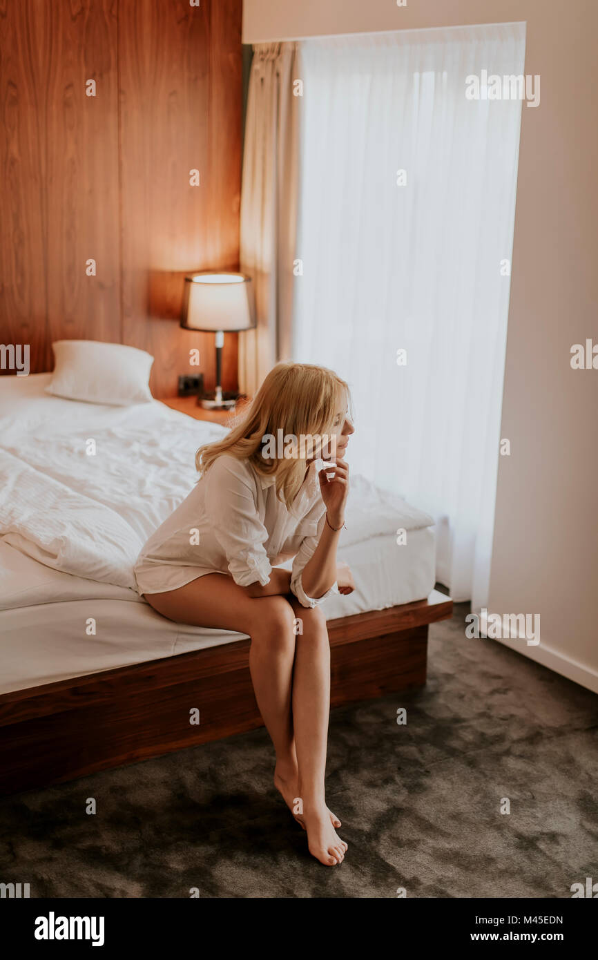 Jeune femme blonde sur le lit de la Chambre l'air heureux et satisfaits Banque D'Images