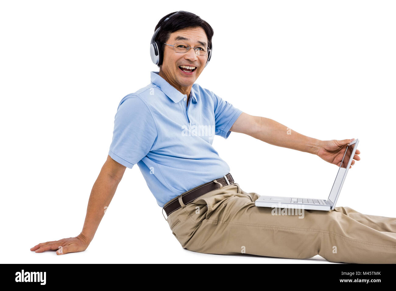 Portrait of cheerful man using laptop while listening music Banque D'Images