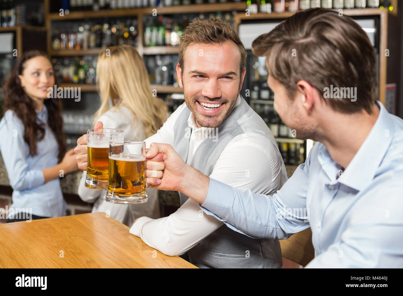 Men toasting en face tandis que les femmes parlent derrière Banque D'Images