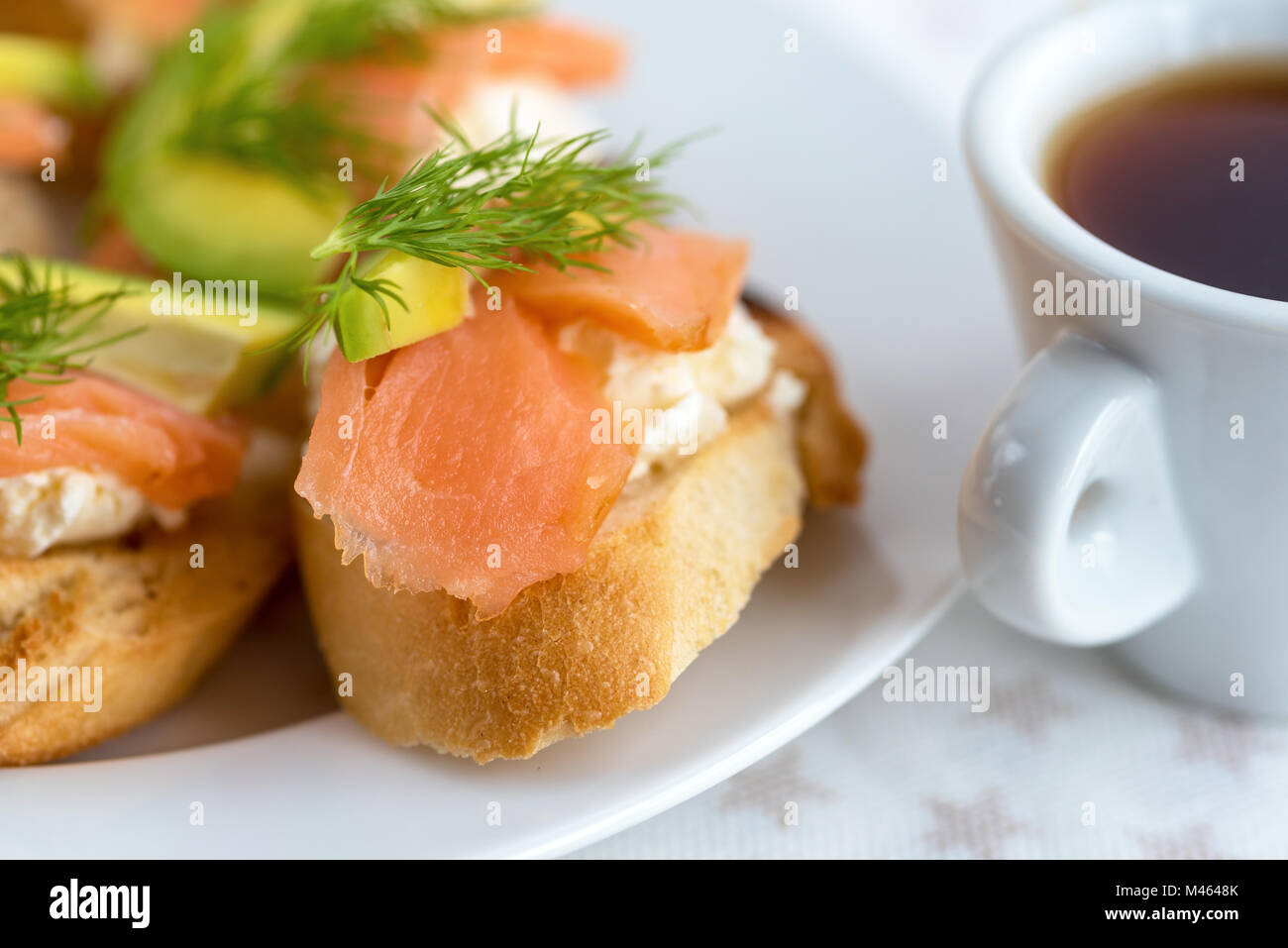 Bruschetta, snack-sandwiches avec du fromage blanc, saumon fumé et morceaux d'avocat décoré par de l'aneth. Banque D'Images