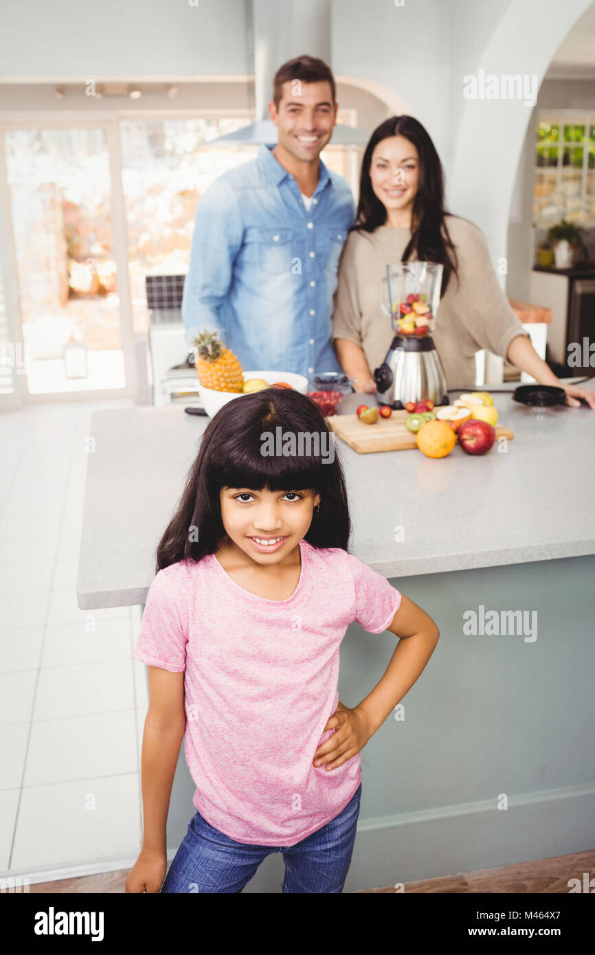 Portrait of smiling girl avec les parents la préparation de lait frappé aux fruits Banque D'Images